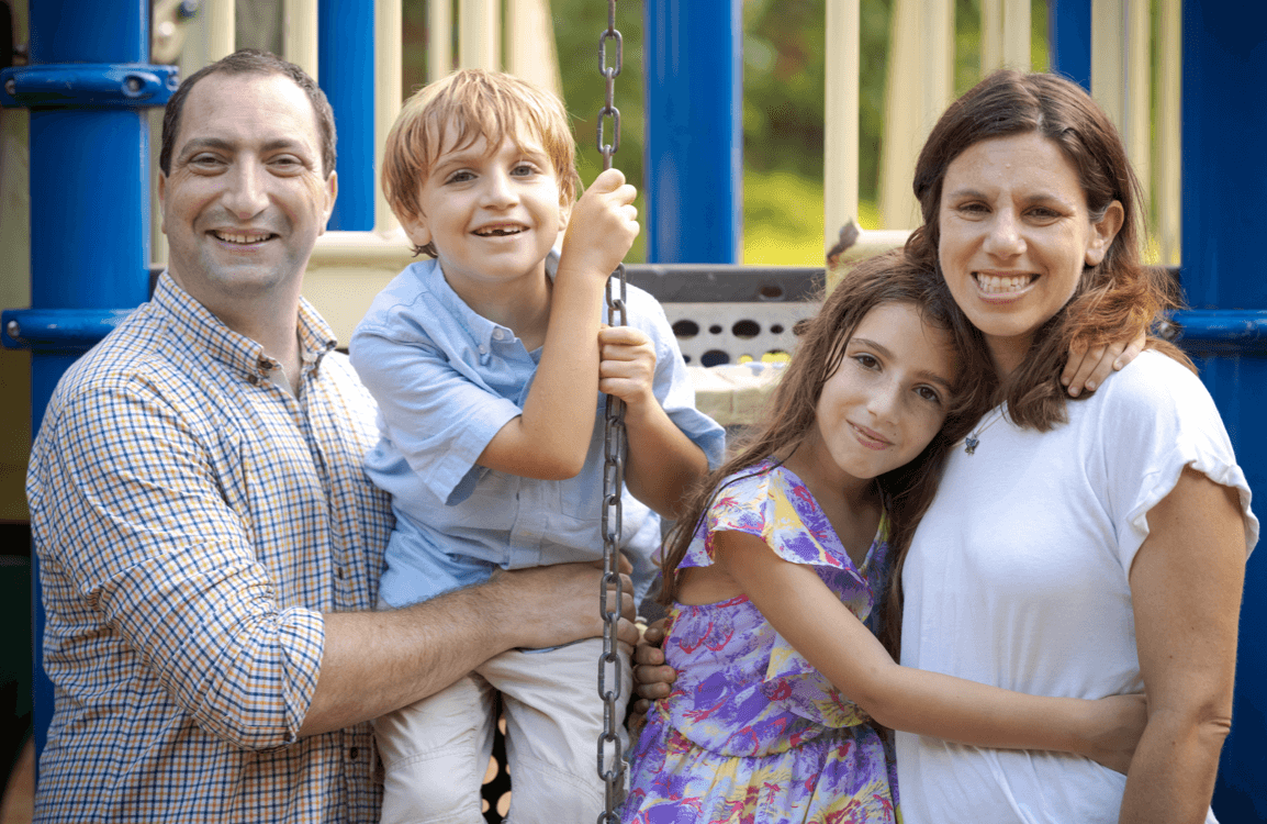 family of four, mother and father with two kids on a porch swing.