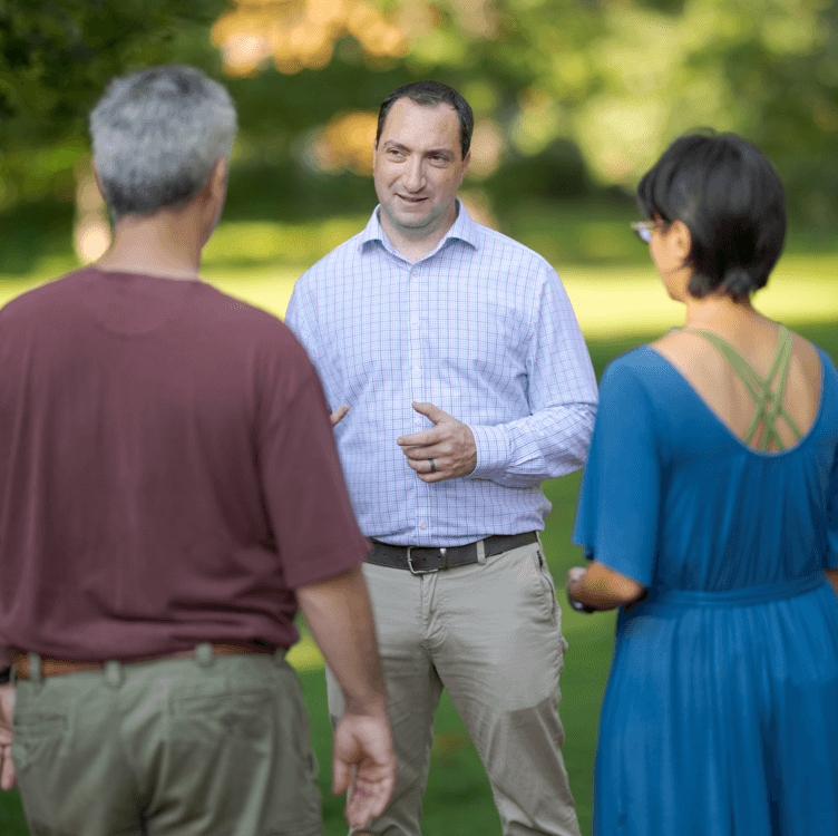 Scott speaking to two people in a park, they have their backs to the camera.